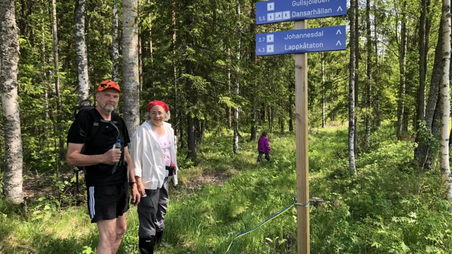 Två personer som står bredvid skyltar efter Gullsjöleden