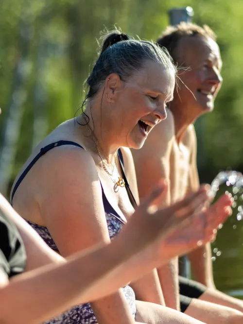 Personer som sitter på en brygga och kastar vatten