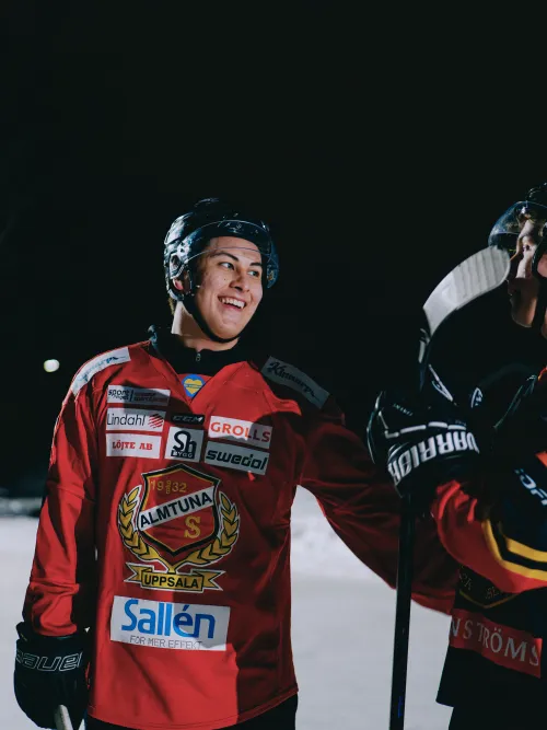 Två personer på isen som pratar med hockeyutrustning