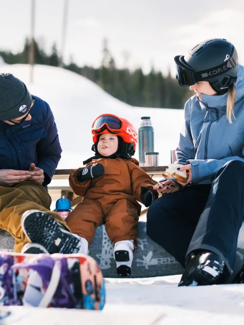 familj som sitter och fikar i skidbacke