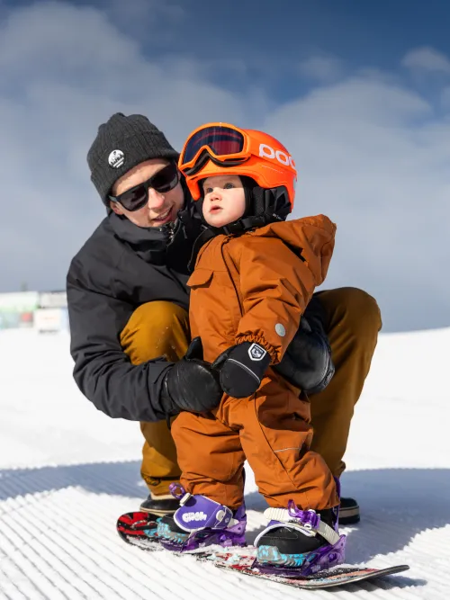 Person som hjälper sitt barn att åka snowboard
