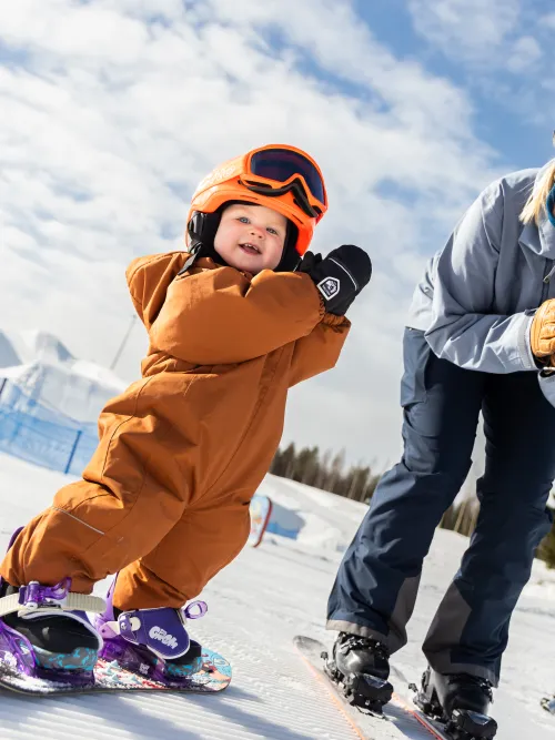 Person som hjälper sitt barn att åka snowboard