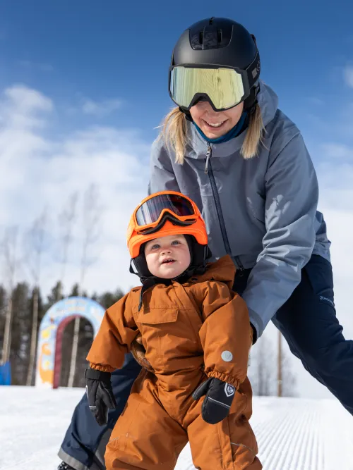 Person som hjälper sitt barn att åka snowboard