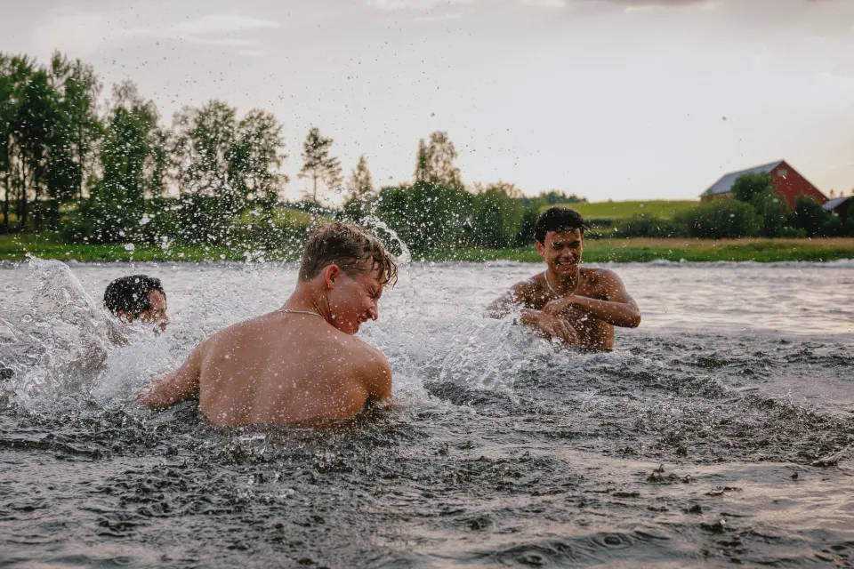 tre personer som badar i älven