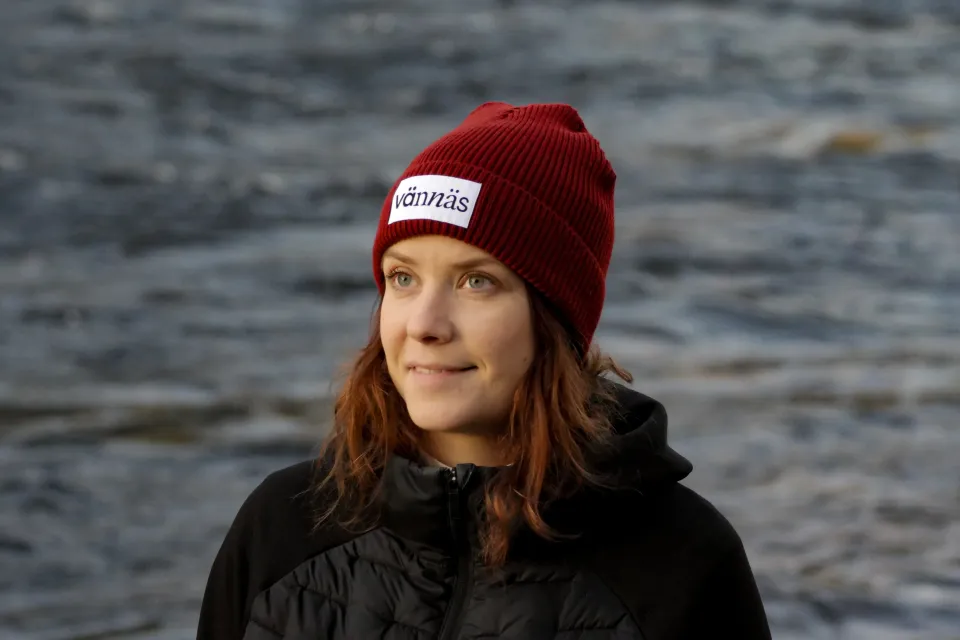 Person som står bredvid älven med mössa