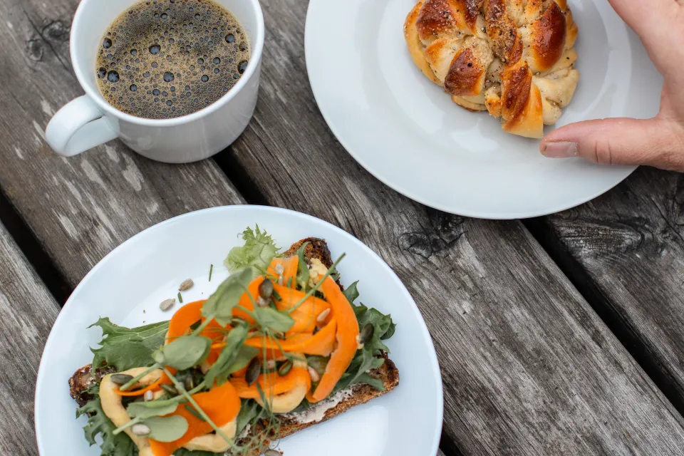 Kaffe, bulle och macka på ett bord