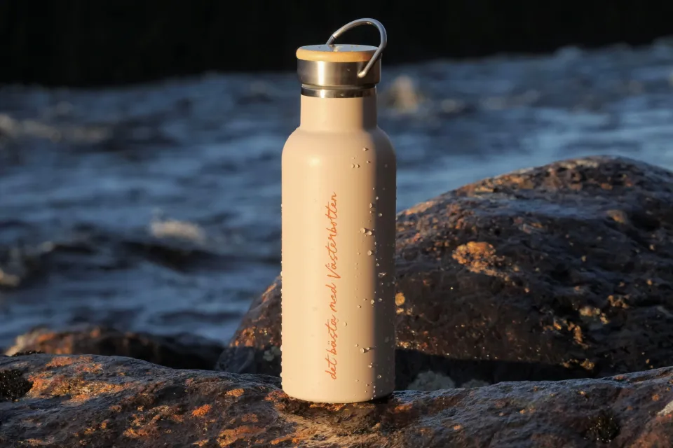 Termosflaska som står på stenar bredvid älv